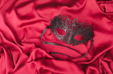 Venetian mask with black feathers on red fabric Stock Photos