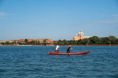 Venetian rowing aboard a typical red boat Stock Photos