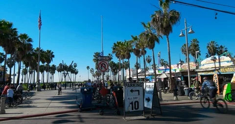 Venice beach boardwalk traffic bikes cars busy california palm trees surf day Stock Footage