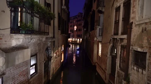 Venice at night. A gondolier with an oar controls a gondola on a narrow canal Stock Footage 284865366