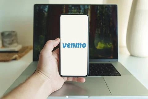 Venmo app logo on cellphone screen. Person holding Venmo application on Stock Photos