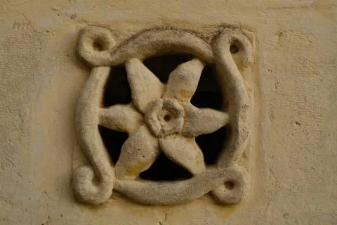 Ventilation grid on the front of a house. Made of stone with a flower shape.  Stock-Fotos