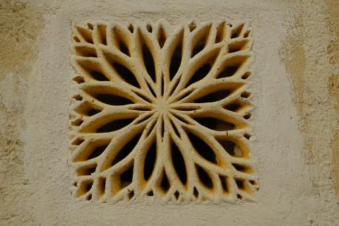 Ventilation grid on the front of a house. Made of stone with a decorative sha Stock Photos