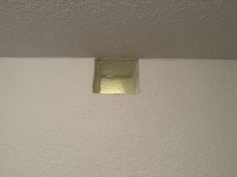 Ventilation opening in interior wall with warm light reflection and texture.. Stock Photos