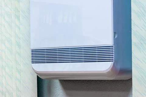 Ventilation openings of a device in a white plastic case mounted on a wall in Stock Photos