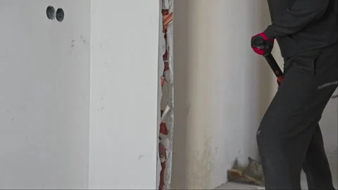 Venting of anger concept. A worker with a sledgehammer demolishes wall Stock Footage 259884676