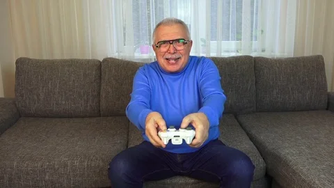 Venturous old man presses console buttons playing video game Stock Footage 108605050
