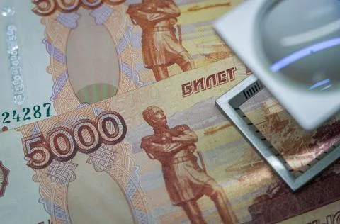 Verification of Russian banknotes for authenticity under a magnifying glass Foto stock