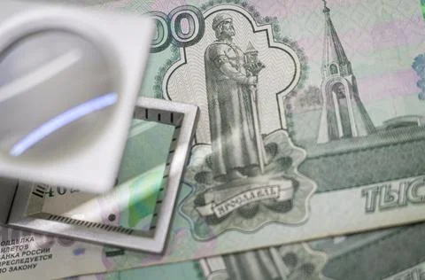 Verification of Russian blurred banknotes for authenticity under a magnifying Stock Photos