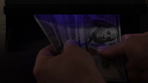 Verifying authenticity of american dollar banknotes under ultraviolet light Stock Footage 307760615