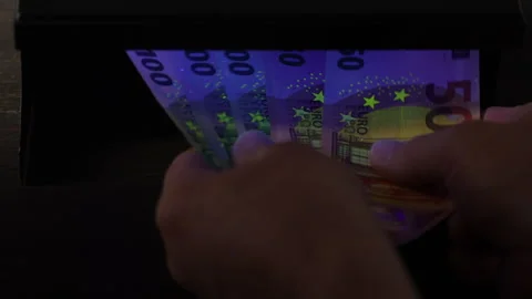 Verifying the authenticity of euro banknotes under ultraviolet light, closeup Stock Footage 306318565