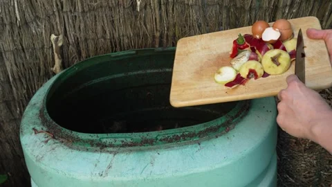 Vermicomposting in the garden, adding kitchen scraps to the compost bin 動画素材 248602294
