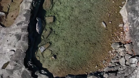 Vertcal footage, studying a rockpool set into balck rocks on the shoreline Stock Footage 331017811