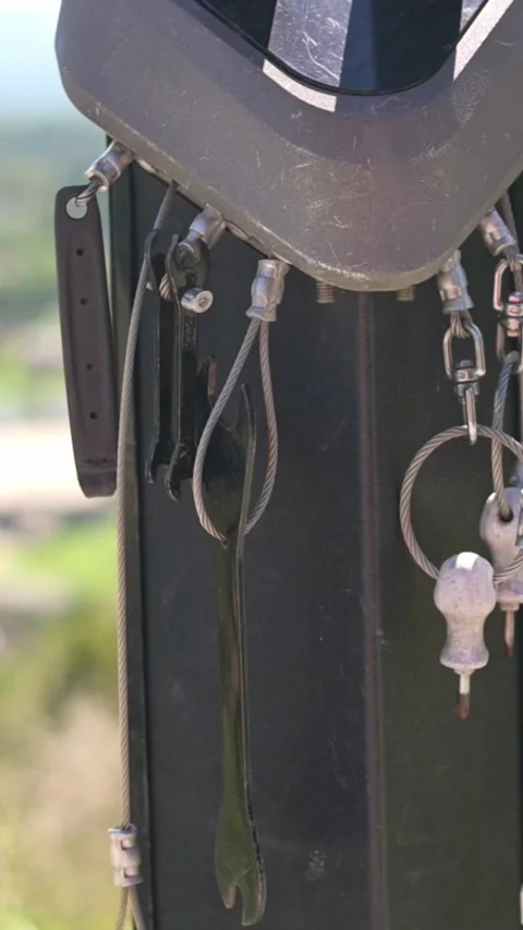 Verti al screen closeup keyring and helmet detail on bike post with blurred park Video stock 323336361