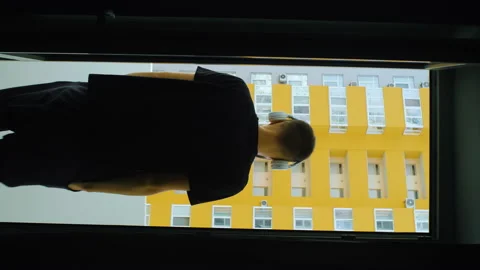 Vertiacal man goes through camera to balcony, looking at camera. male in Stock Footage 168689431