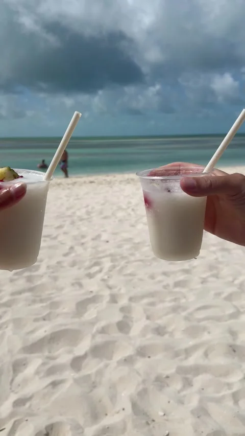 Vertical 4K Close Up Of Couple Clinking Pina Colada Plastic Cups On Beach Stock Footage 335549076