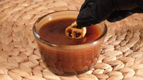 Vertical 4K Close Up Hand Dipping Pretzel into Salted Caramel Stock Footage 334784438