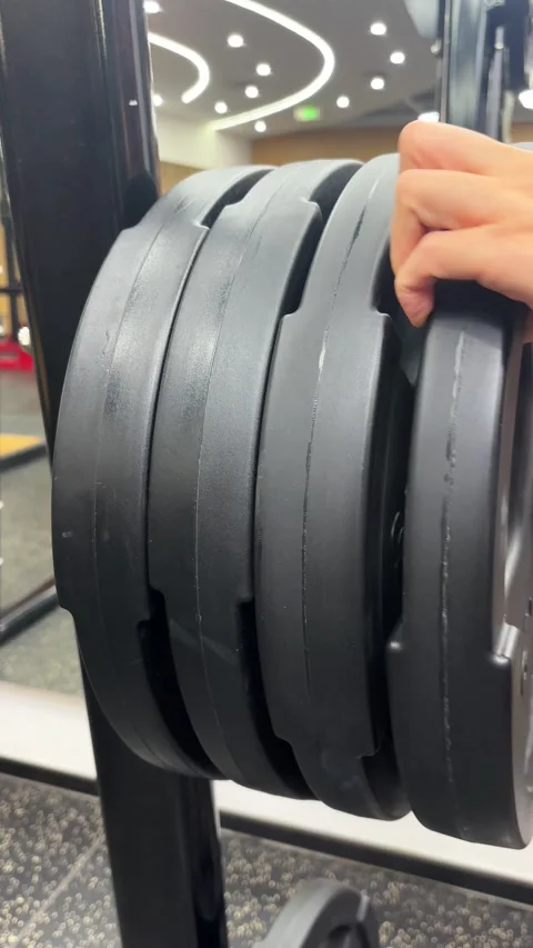 Vertical 4K Close Up of Hand Placing Weight Plate on Machine Stock Footage 329336569