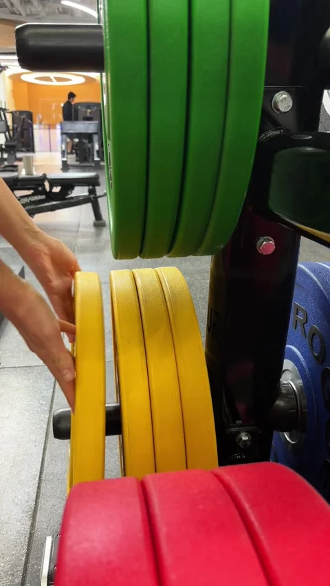 Vertical 4K Close Up of Hand Putting Rogue Weight Back on Rack Stock Footage 329336590