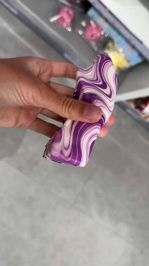 Vertical 4K close-up of a hand squeezing a purple and white butter squishy toy Stock Footage 342061509