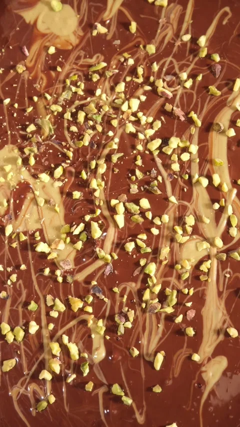 Vertical 4K Close Up of Liquid Dark Chocolate with Pistachio Paste and Nuts Stock Footage 334780914