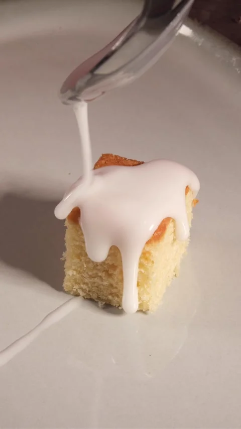 Vertical 4K Close Up of White Icing Pouring onto Mini Sponge Cake Stock Footage 333319561