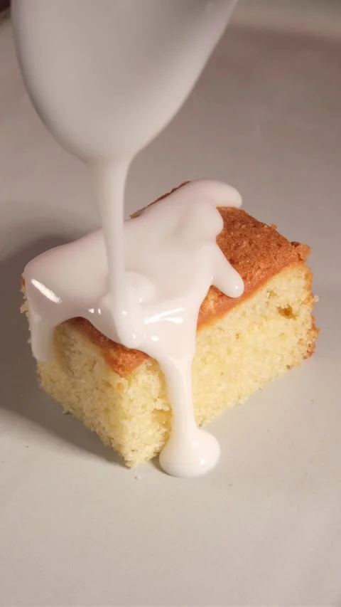 Vertical 4K Close Up of White Icing Pouring from Spoon onto Cake 스톡 동영상 333319732
