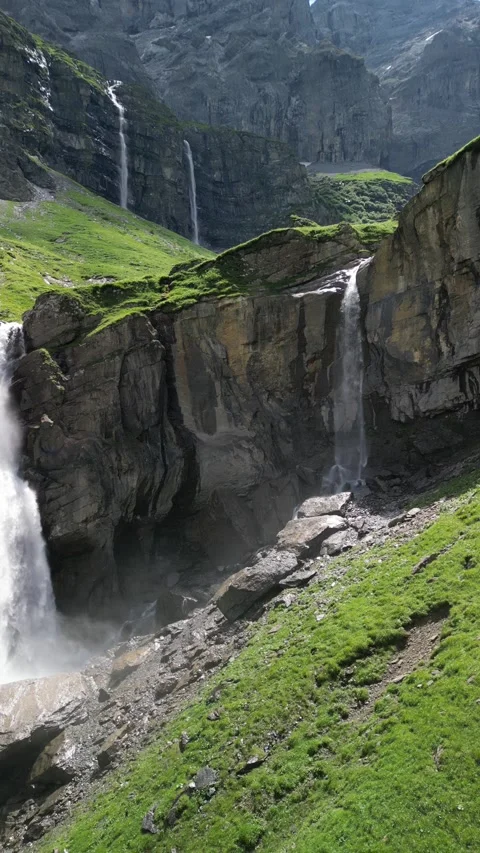 Vertical 4K Drone Shot of Tall Alpine Waterfall Cascading Over Rocky Cliffs Video stock 328706135