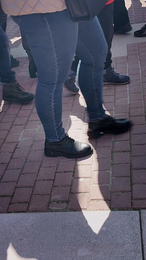 Vertical 4k editorial footage focused on moving legs and shadows across paved Stock Footage 331621628