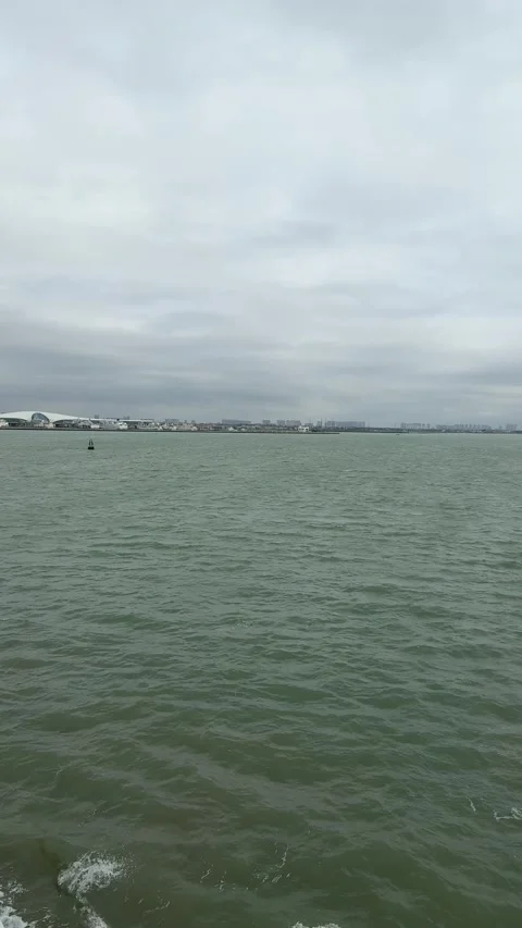 Vertical 4K Ferry Approaching Port with Distant Haikou City Skyline Stock-Footage 332037404