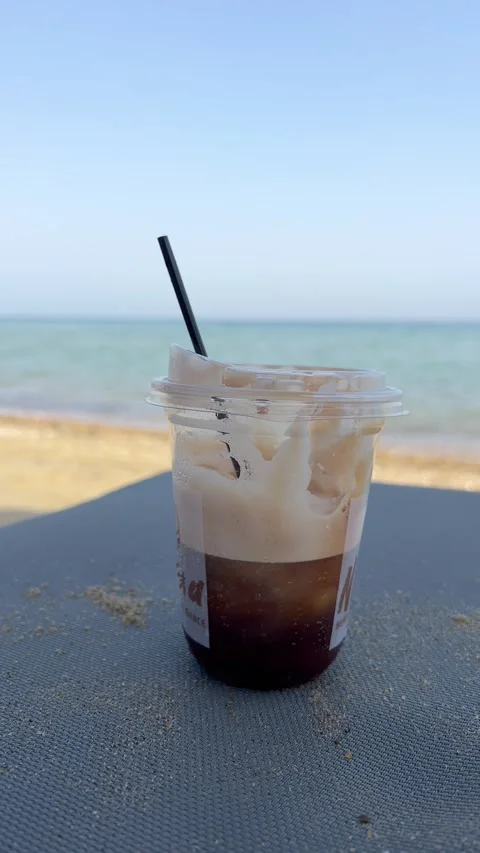 Vertical 4K Freddo Cappuccino by the Sea on Perea Beach, Greece Stock Footage 346421101