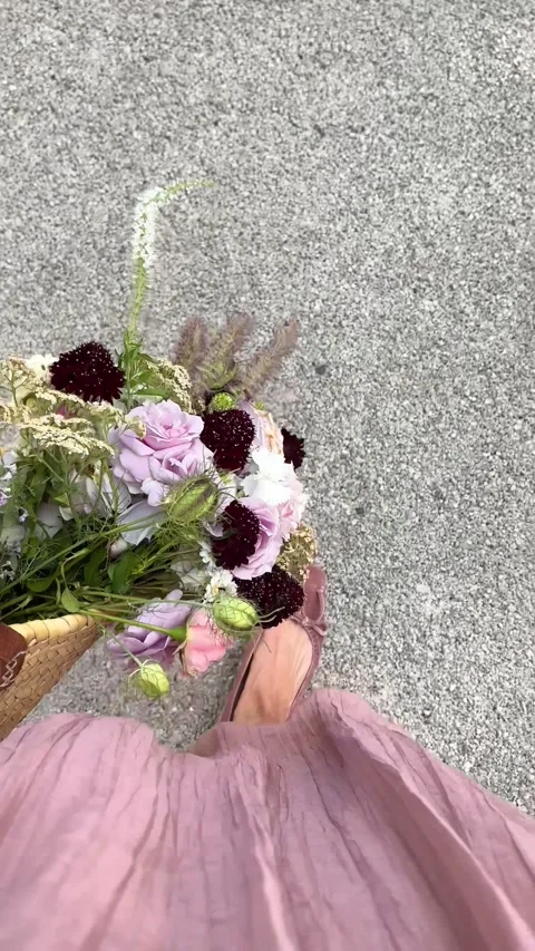 Vertical 4K handheld POV of pink dress moving with summer flower basket. 스톡 동영상 337795699