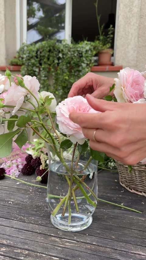 Vertical 4K handheld shot of placing roses in glass vase on table. 스톡 동영상 337910071