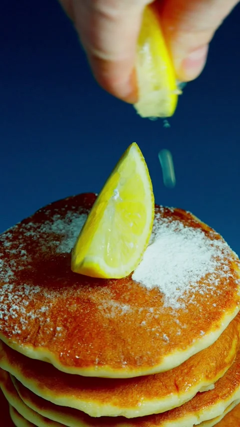 Vertical 4K lemon juice squeezed over rotating pancakes, Shrove Tuesday food Stock Footage 328318833