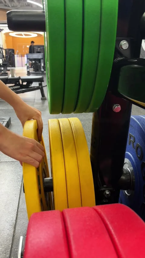 Vertical 4K Macro of Hand Removing Rogue Iron Weight Plate Stock Footage 329336713