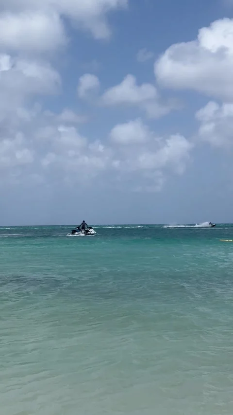 Vertical 4K Man Riding Jet Ski To White Sand Shore In Aruba Vídeos de archivo 335372619