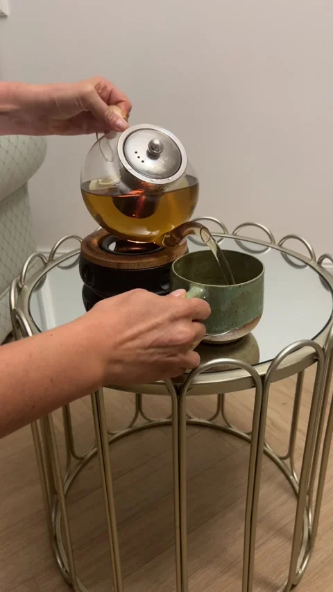 Vertical 4K - Pouring Hot Tea From Glass Teapot Into Ceramic Mug Coziness Stock Footage 345443471