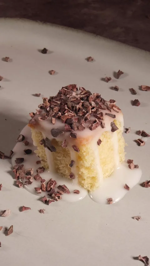 Vertical 4K Raw Cocoa Nibs Falling on White Iced Sponge Cake 스톡 동영상 333319225