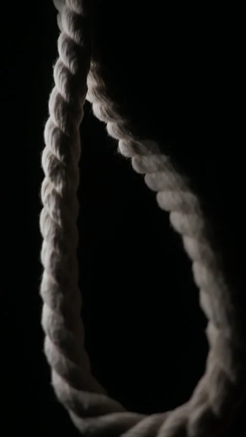 Vertical 4K shot of a hanging rope noose on black background Vidéo 332889633