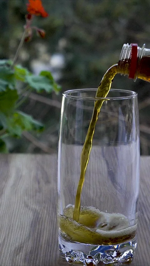 Vertical 4K Slow Motion of Dark Soda Drink Pouring into Glass Cup Stock Footage 331313596