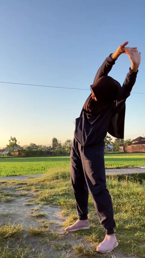 Vertical 4K Slow Motion Muslim Woman in Hijab Stretching Arms at Sunrise in Coun Stock Footage 337999619