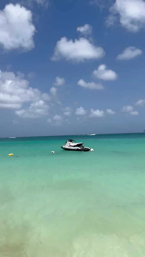 Vertical 4K Sunny Eagle Beach Aruba With Turquoise Waves And Distant Jet Ski Vídeos de archivo 335372661