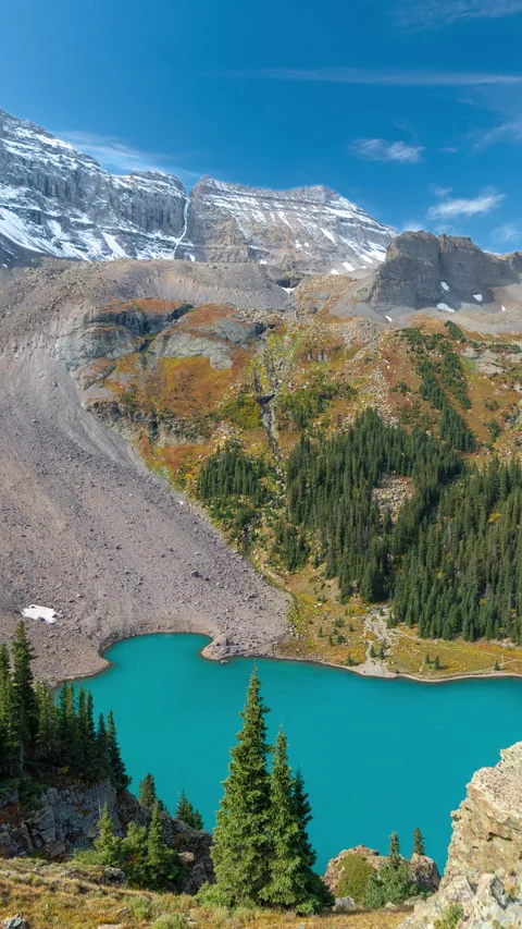 Vertical 4k Timelapse, Turquoise Alpine Lake Under Green Hills and Snow Stock Footage 276546735