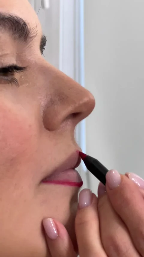 Vertical 4K video. 60 fps. Make up artist draws dark red contour on lips Stock Footage 308127293
