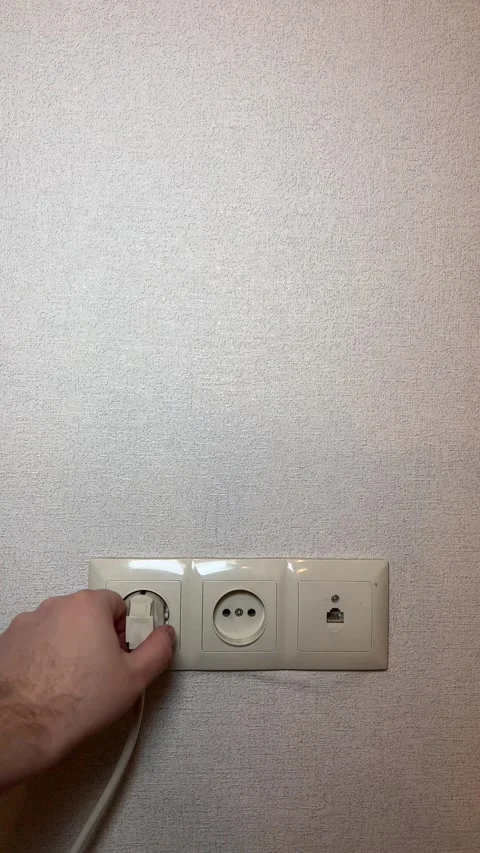 Vertical 4K video. 60 fps. Male hand pulls out white plug from an extension cord Stock Footage 308922890