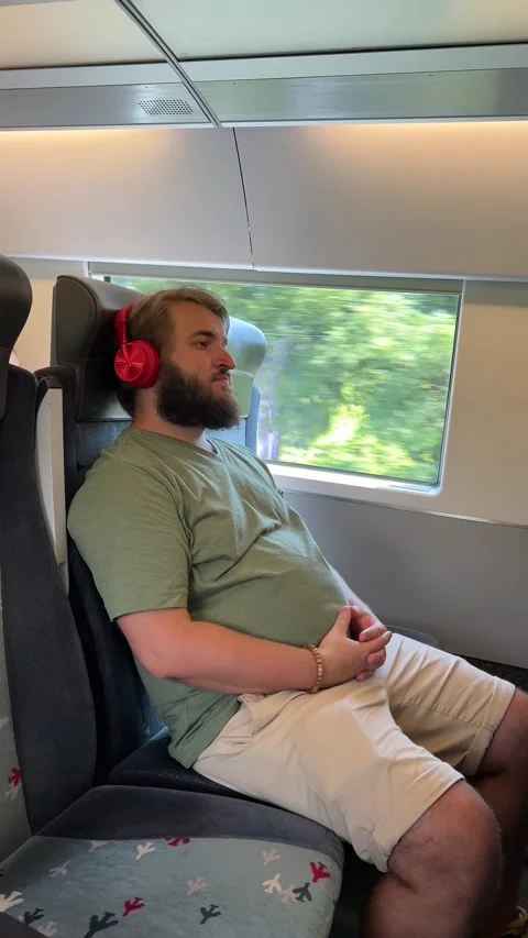 Vertical 4K video. Bearded man sits and listens to music on seat in train Stock Footage 290136031