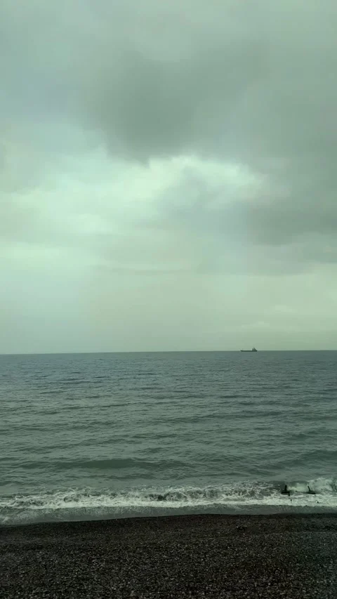 Vertical 4K video. Camera moves along Black Sea coast. Gray cloudy sky Stock Footage 277467106