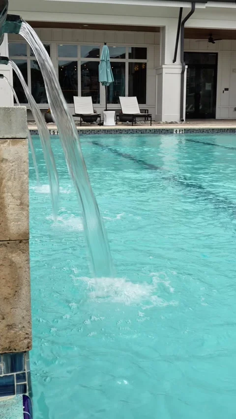Vertical 4K video of clear water flowing from a fountain into swimming pool Stock Footage 342078149
