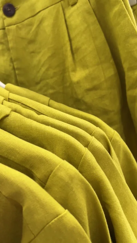 Vertical 4K video close up. Yellow shirt on hanger in clothing store Video stock 314828573
