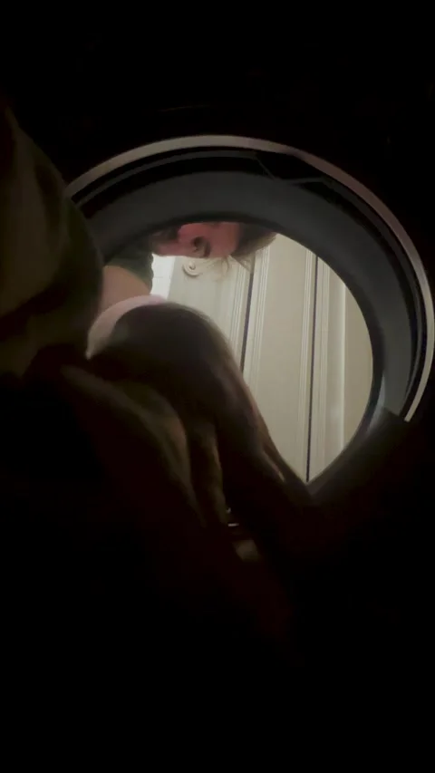 Vertical 4K video. Inside view. Man puts laundry into round washing machine Stock Footage 333594319
